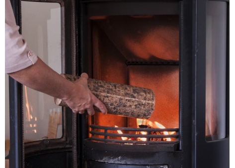 Holzscheit wird in den Ofen gelegt